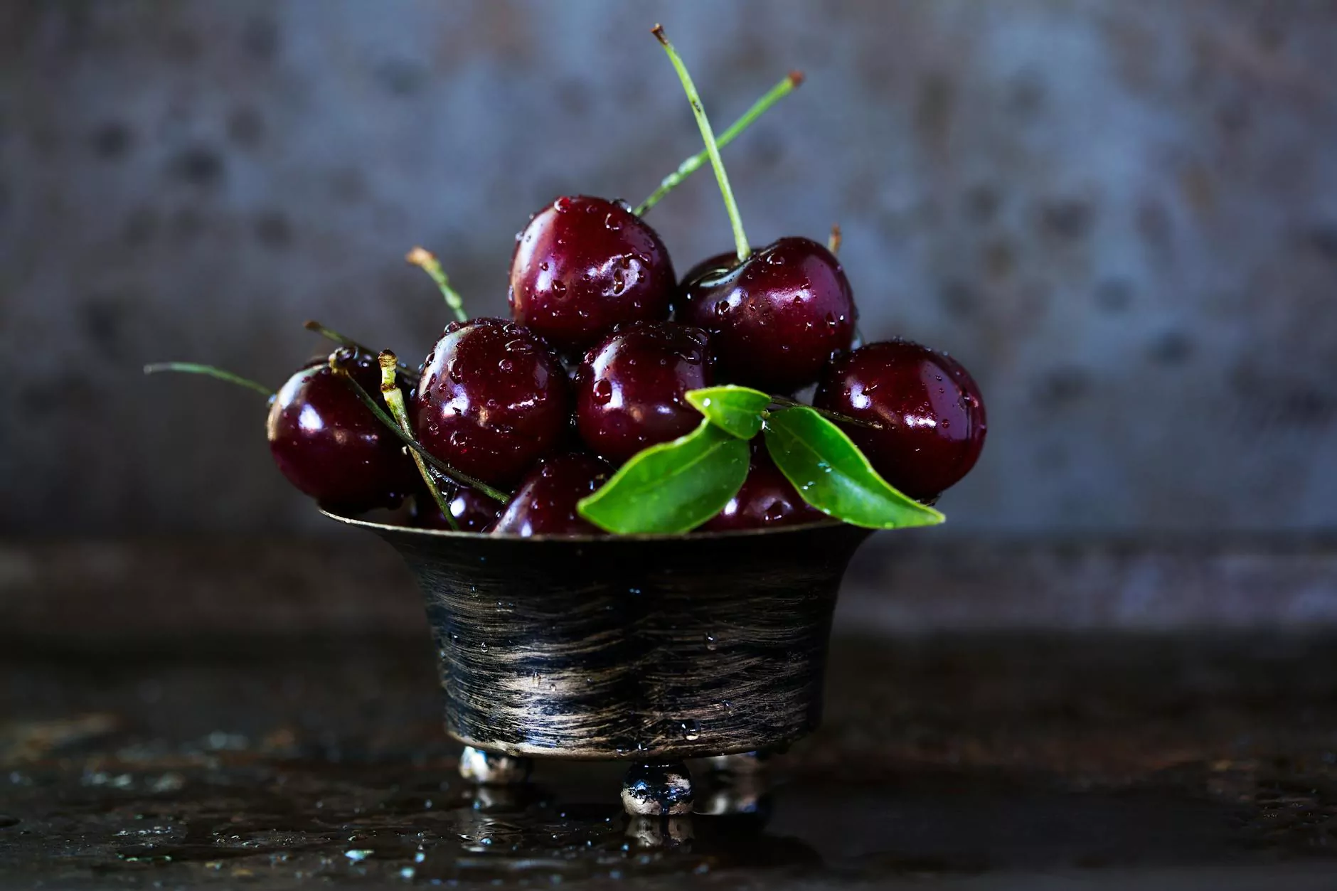 A small cluster of whole dark cherries with green stems
